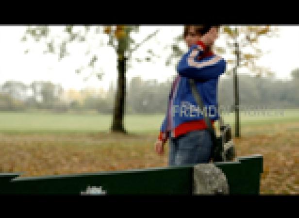 Eine junge Frau steht in einem Park und blickt in die Ferne.