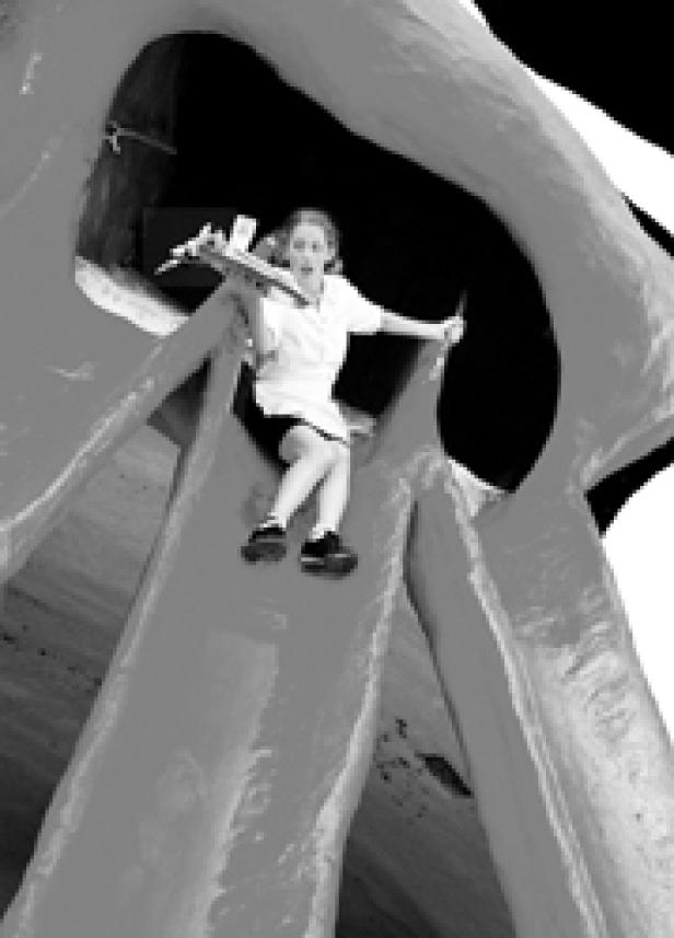 Ein Mädchen rutscht eine hohe Rutsche hinunter.