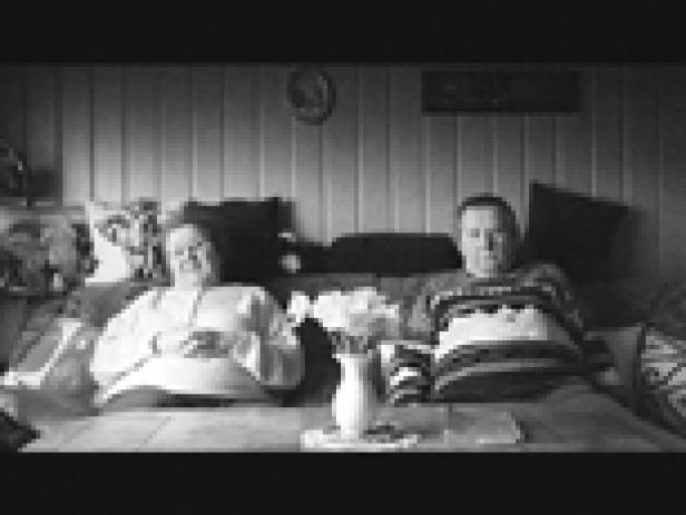 Ein älteres Paar sitzt auf einem Sofa in einem Wohnzimmer.