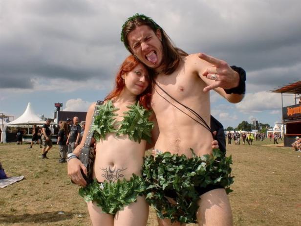Ein Paar, spärlich mit Blättern bekleidet, posiert auf einem Festivalgelände.