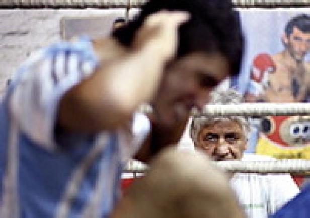 Ein Boxer steht im Ring, während ein älterer Mann ihm aufmerksam zusieht.