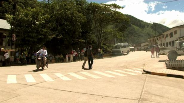 Ein Mann fährt mit einem Motorrad über einen Zebrastreifen in einer Stadt.