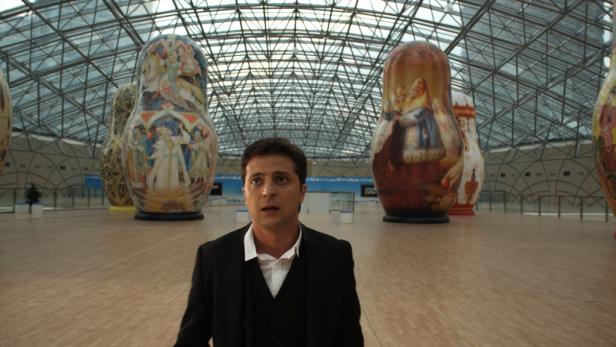 Wolodymyr Selenskyj steht vor überdimensionalen Matroschka-Puppen in einer Halle.