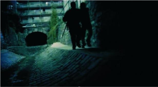 Zwei dunkle Silhouetten gehen nachts an einem Bach entlang.