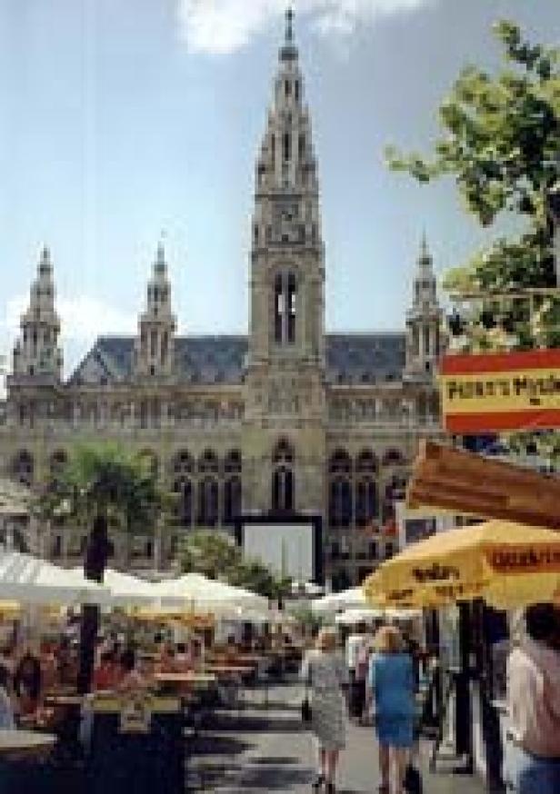 Das Wiener Rathaus überblickt einen belebten Markt mit Essensständen.
