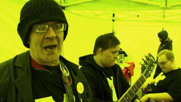 Eine Band spielt unter einem gelben Zelt Musik.