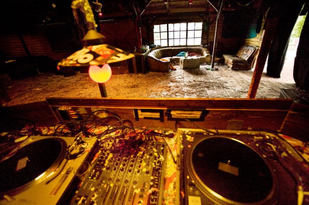 Ein DJ-Pult steht in einem Raum mit Sofas und einer ungewöhnlichen Dekoration.