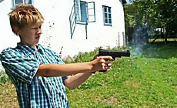Ein junger Mann zielt mit einer Pistole in einem Garten.