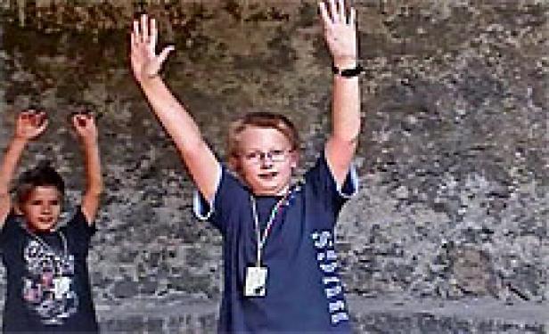 Zwei Jungen stehen vor einer Wand und heben die Arme.