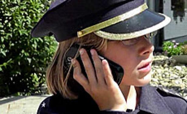Ein Kind in Polizeiuniform telefoniert mit einem Smartphone.