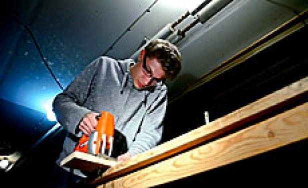 Ein Mann sägt ein Holzbrett mit einer Stichsäge.