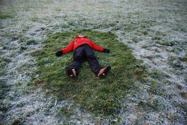 Eine Person liegt auf einer Wiese mit Frost.