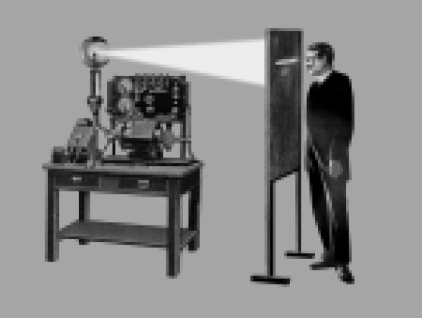 Ein Mann steht vor einer Maschine, die sein Gesicht mit Licht bestrahlt.