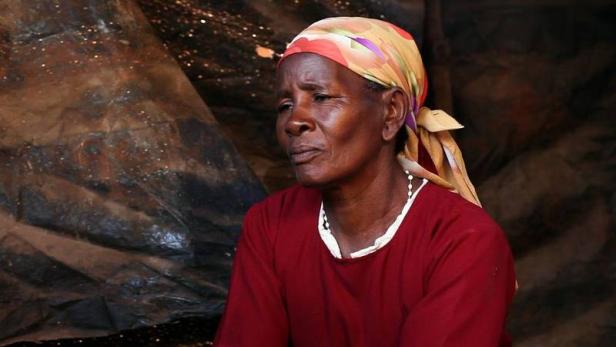 Eine Frau mit Kopftuch und rotem Oberteil blickt nachdenklich zur Seite.