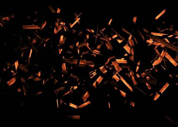 Viele kleine Holzstücke scheinen in der Dunkelheit zu schweben.