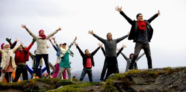 Eine Gruppe von Menschen steht mit erhobenen Armen auf einem Hügel.