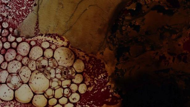 Abstrakte Nahaufnahme von Blasen und Texturen in Rot-, Braun- und Goldtönen.