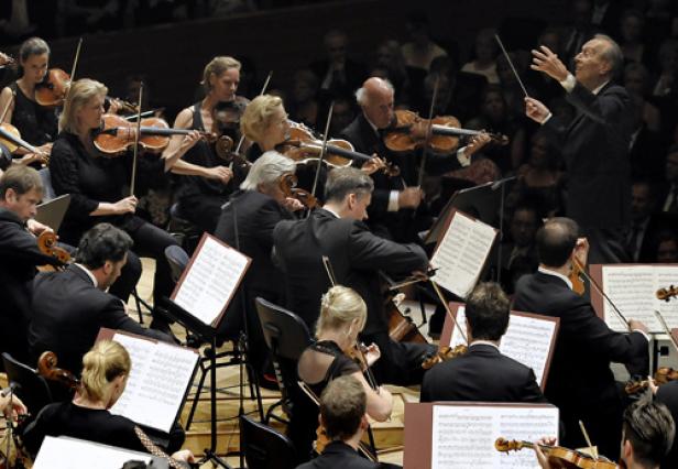 Ein Orchester spielt unter der Leitung eines Dirigenten in einem Konzertsaal.