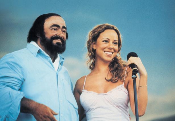 Luciano Pavarotti und Mariah Carey stehen zusammen vor einem blauen Hintergrund.
