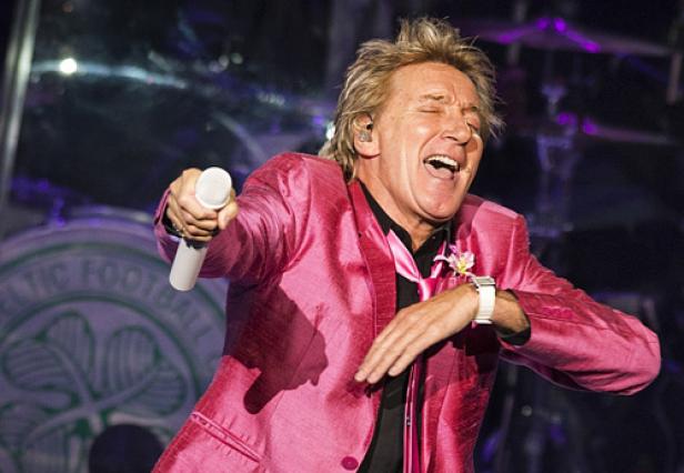 Rod Stewart tritt in einem pinkfarbenen Anzug auf der Bühne auf.