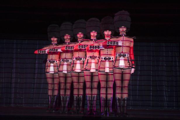 Eine Gruppe von Tänzerinnen in Gardeuniformen auf einer Bühne.