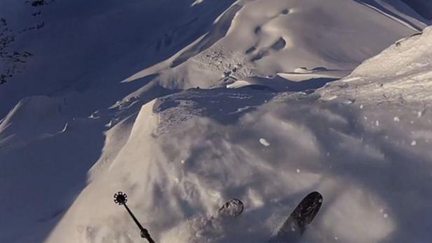 Ein Skifahrer fährt einen steilen, schneebedeckten Hang hinunter.