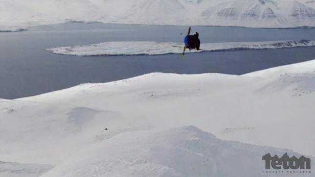 Ein Skifahrer springt vor einer verschneiten Berglandschaft in der Luft.