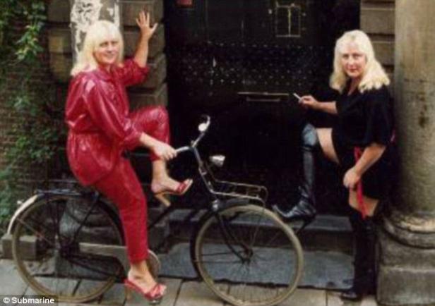 Zwei Frauen posieren mit einem Fahrrad vor einer dunklen Tür.