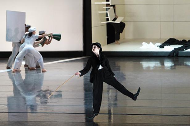 Eine Tanzperformance mit einer Person im Charlie-Chaplin-Kostüm im Vordergrund.