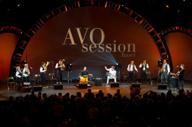 Eine Musikgruppe tritt bei der AVO Session Basel vor Publikum auf einer Bühne auf.
