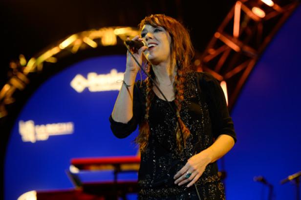 Eine Frau mit Zöpfen singt auf einer Bühne in ein Mikrofon.