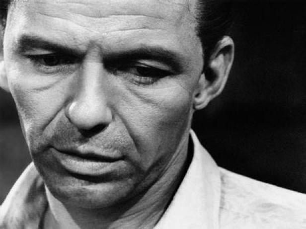 Ein Schwarzweißporträt von Frank Sinatra, der nachdenklich nach unten blickt.