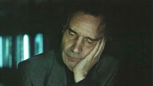 Ein Mann in einem dunklen Raum stützt seinen Kopf in seiner Hand.