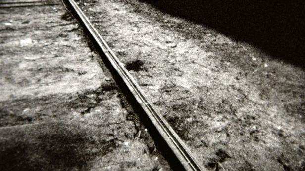 Eine Schwarz-Weiß-Aufnahme einer Landstraße, die sich durch eine karge Landschaft zieht.