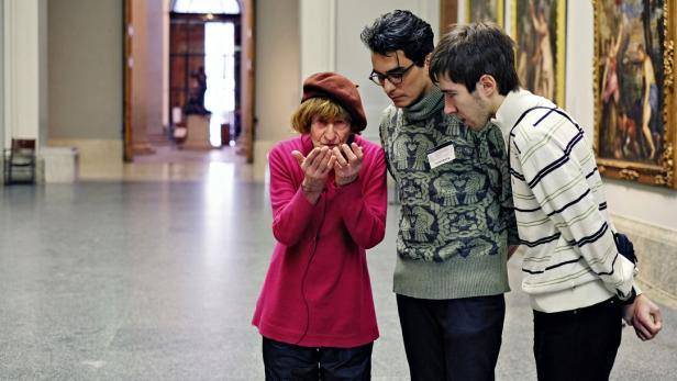 Drei Personen betrachten ein Kunstwerk in einem Museum.