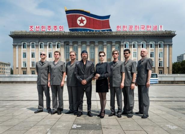 Die slowenische Band Laibach posiert vor einem Gebäude in Nordkorea unter einer nordkoreanischen Flagge.