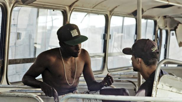 Zwei Männer sitzen in einem alten Bus und unterhalten sich.