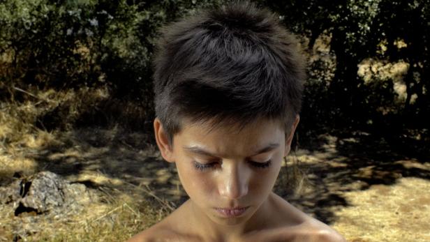 Ein junger Mann mit dunklen Haaren blickt nach unten.