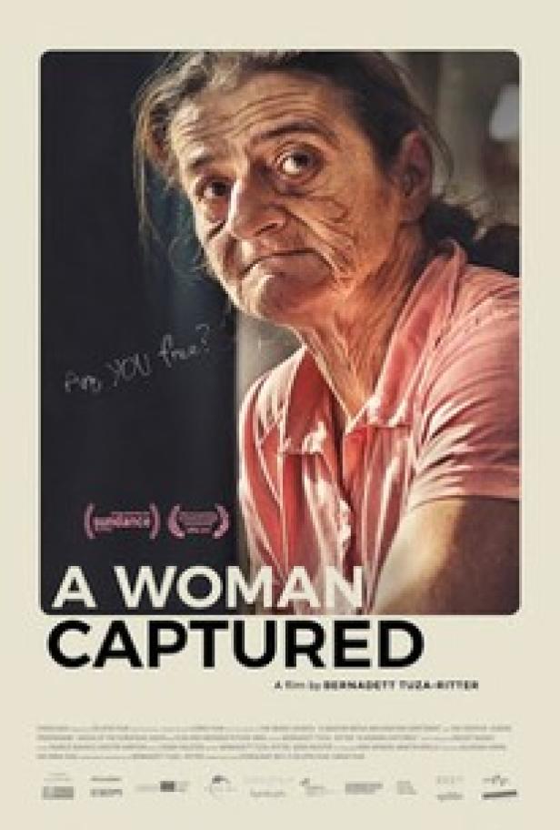 Das Filmplakat für „A Woman Captured“ zeigt eine ältere Frau in einem rosa Hemd.