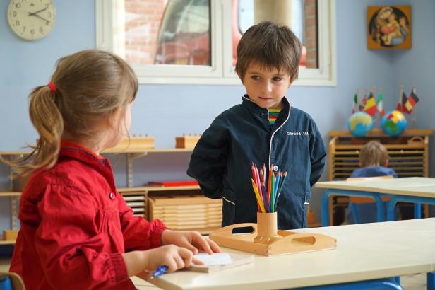 Zwei Kinder sitzen in einem Klassenzimmer an einem Tisch.