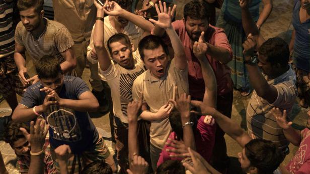 Eine Gruppe von Menschen jubelt und hebt die Hände in die Luft.