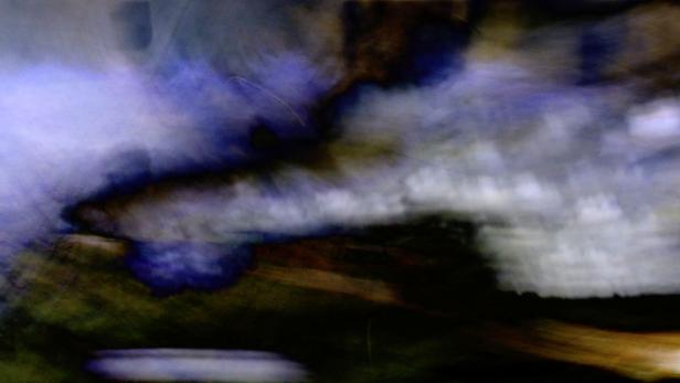 Eine verschwommene Darstellung von dunklen und hellen Farbtönen, die eine abstrakte Landschaft suggerieren.