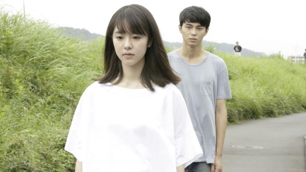 Eine junge Frau und ein junger Mann stehen auf einem Weg in ländlicher Umgebung.