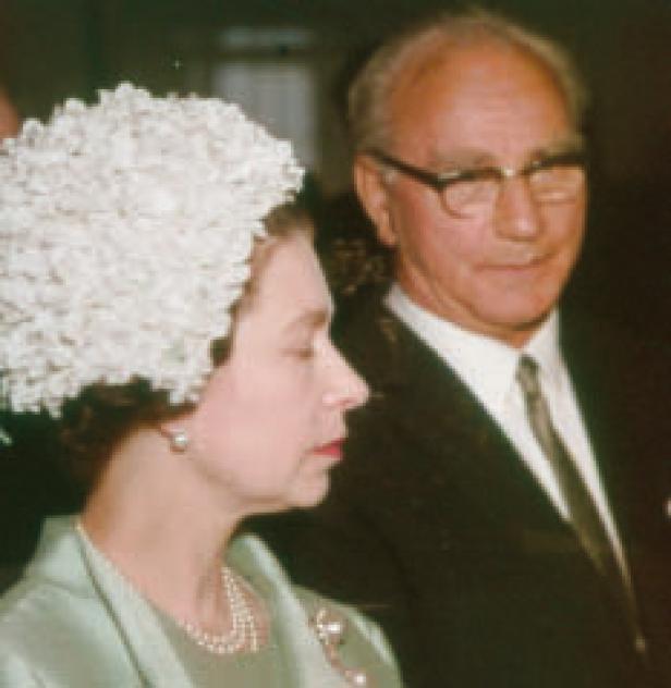 Königin Elisabeth II. mit einem Mann im Anzug.