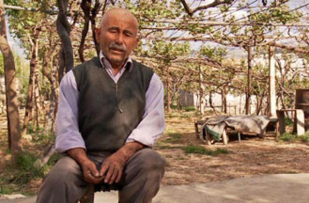 Ein älterer Mann sitzt auf einem Stuhl im Freien.