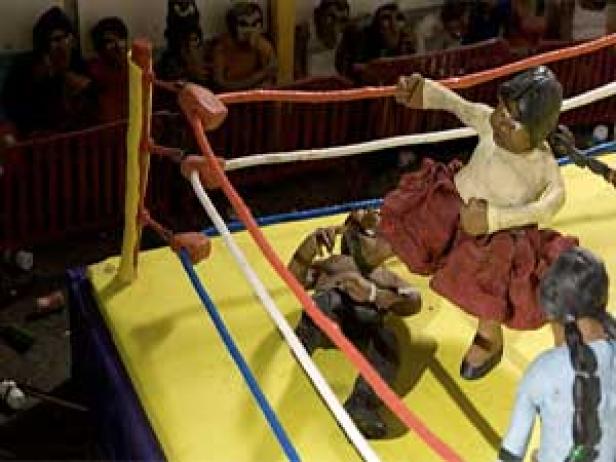 Eine Wrestling-Szene mit Figuren in einem Ring, dargestellt in einem handwerklichen Stil.