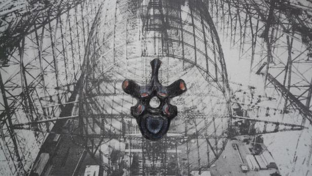 Eine Wirbelattrappe vor dem Hintergrund einer Schwarz-Weiß-Zeppelinwerft.