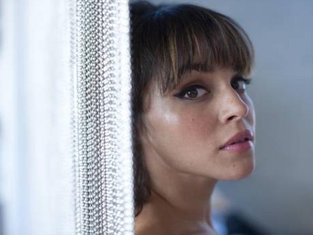 Eine Frau mit Pony und dunklem Eyeliner blickt in die Kamera.