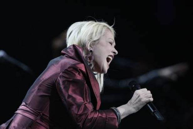 Cyndi Lauper singt während eines Auftritts mit einem Mikrofon in der Hand.
