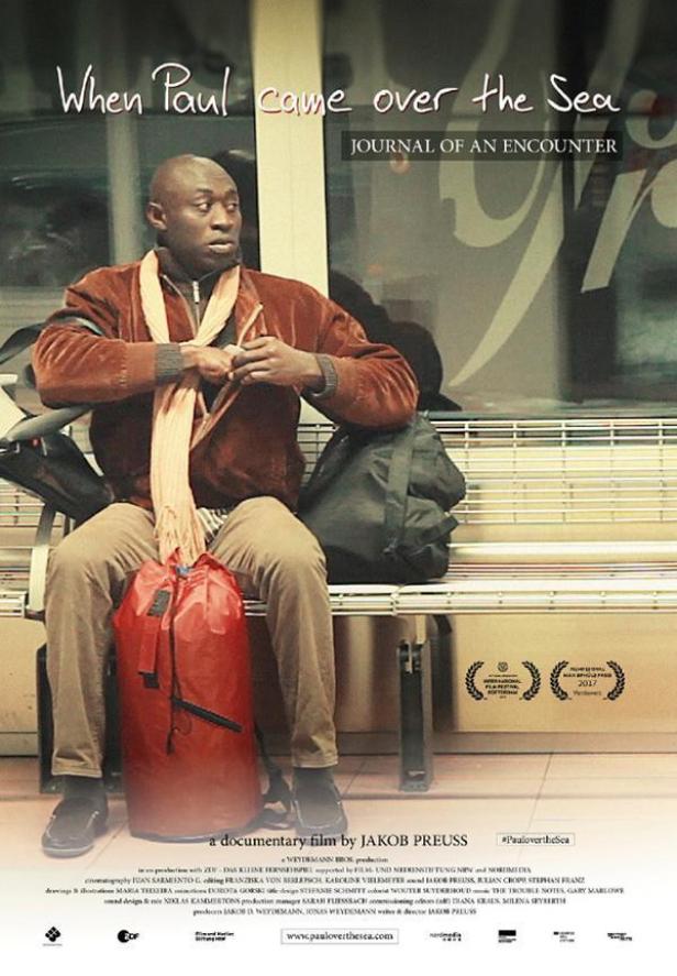 Ein Mann sitzt auf einer Bank mit einer roten Tasche, Plakat für den Film „When Paul came over the Sea“.